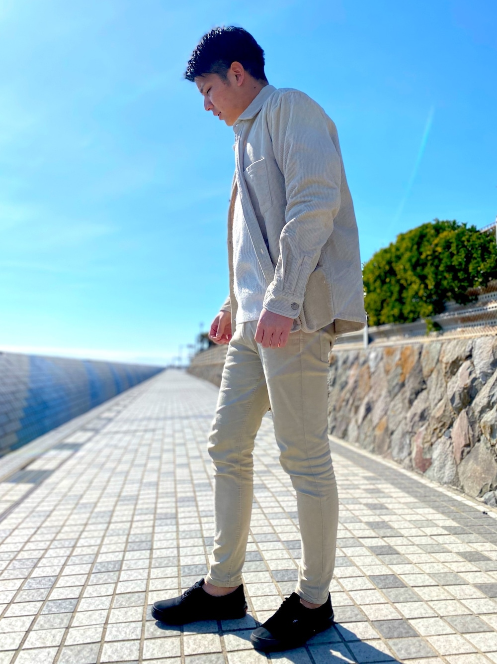 ベージュ系のチノパンツ、ブラック系のスニーカー、ホワイト系のニット/セーターを着用したメンズの冬コーディネートの1枚目の写真