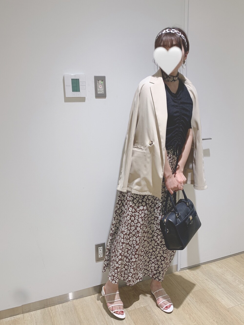 ブルー系のバッグ、ブラウン系のスカート、ブラック系のトップスを着用したレディースの春コーディネートの1枚目の写真