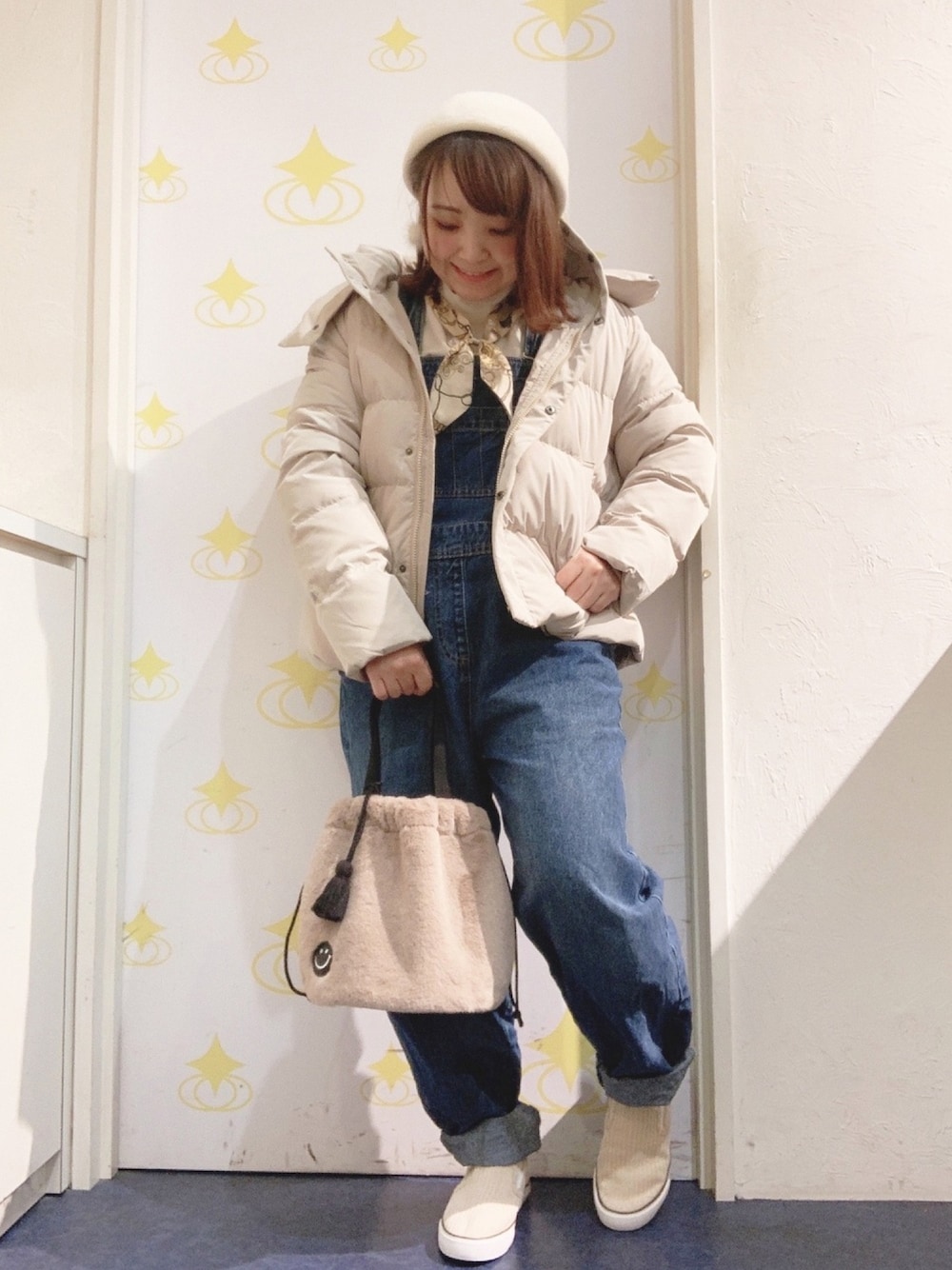 ホワイト系のTシャツ/カットソー、ブルー系のサロペット/オーバーオール、ベージュ系のダウンジャケット/コートを着用したレディースの冬コーディネートの1枚目の写真