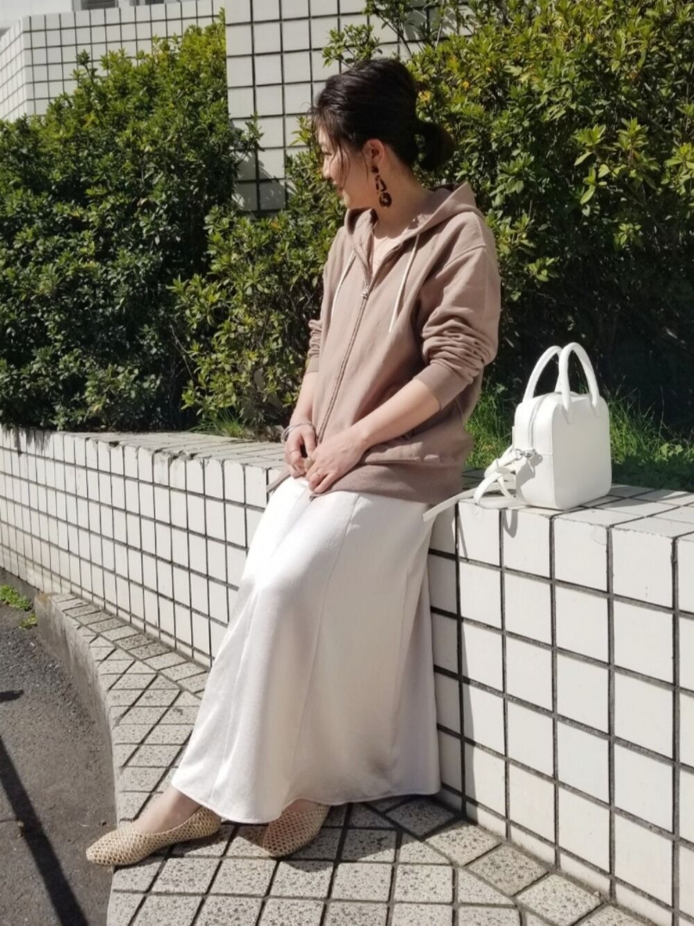 ホワイト系のハンドバッグ、ベージュ系のバレエシューズ、イエロー系のパーカーを着用したレディースの冬コーディネートの1枚目の写真