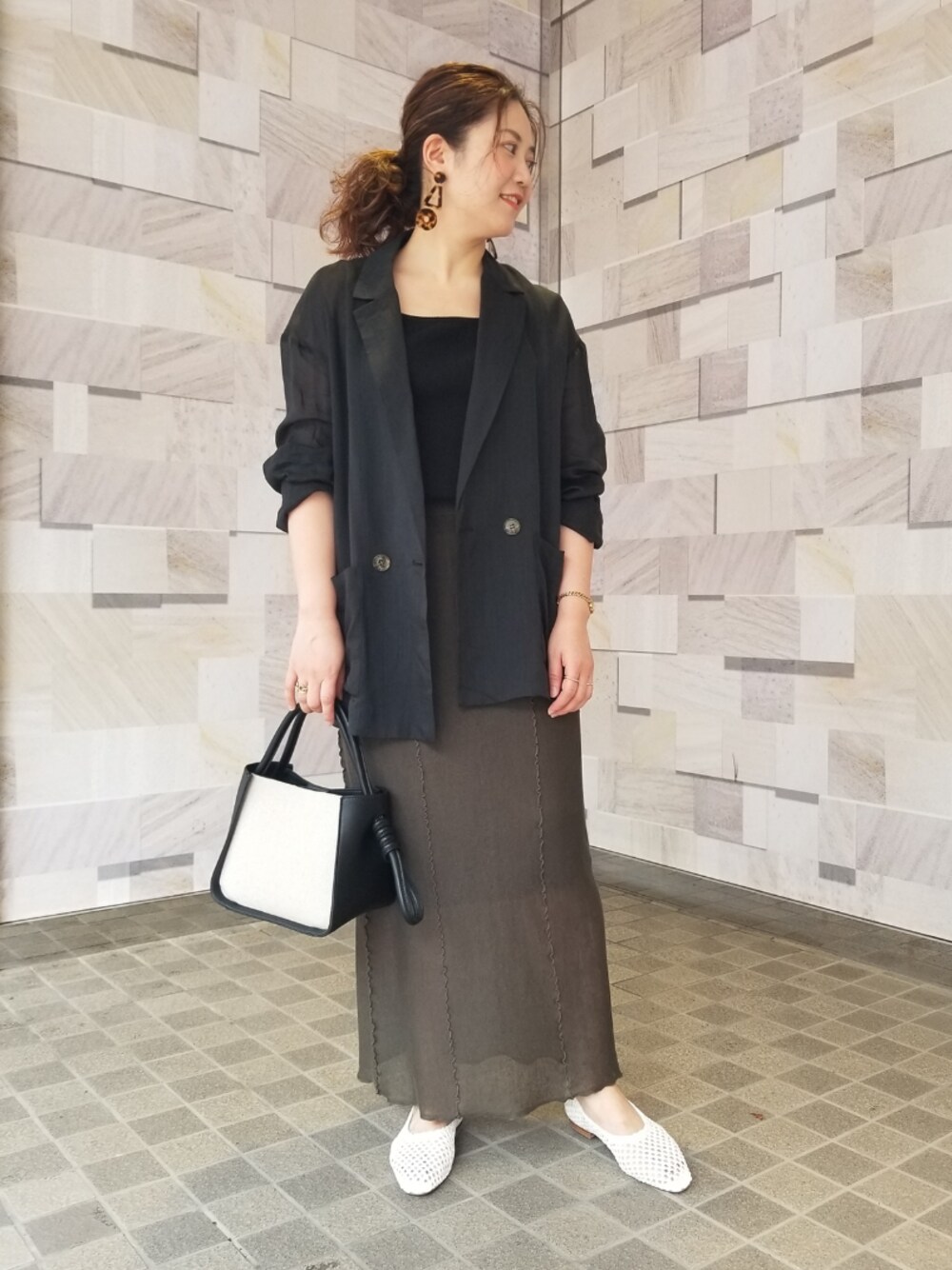 ブラック系のハンドバッグ、ホワイト系のバレエシューズ、グリーン系のスカートを着用したレディースの夏コーディネートの1枚目の写真