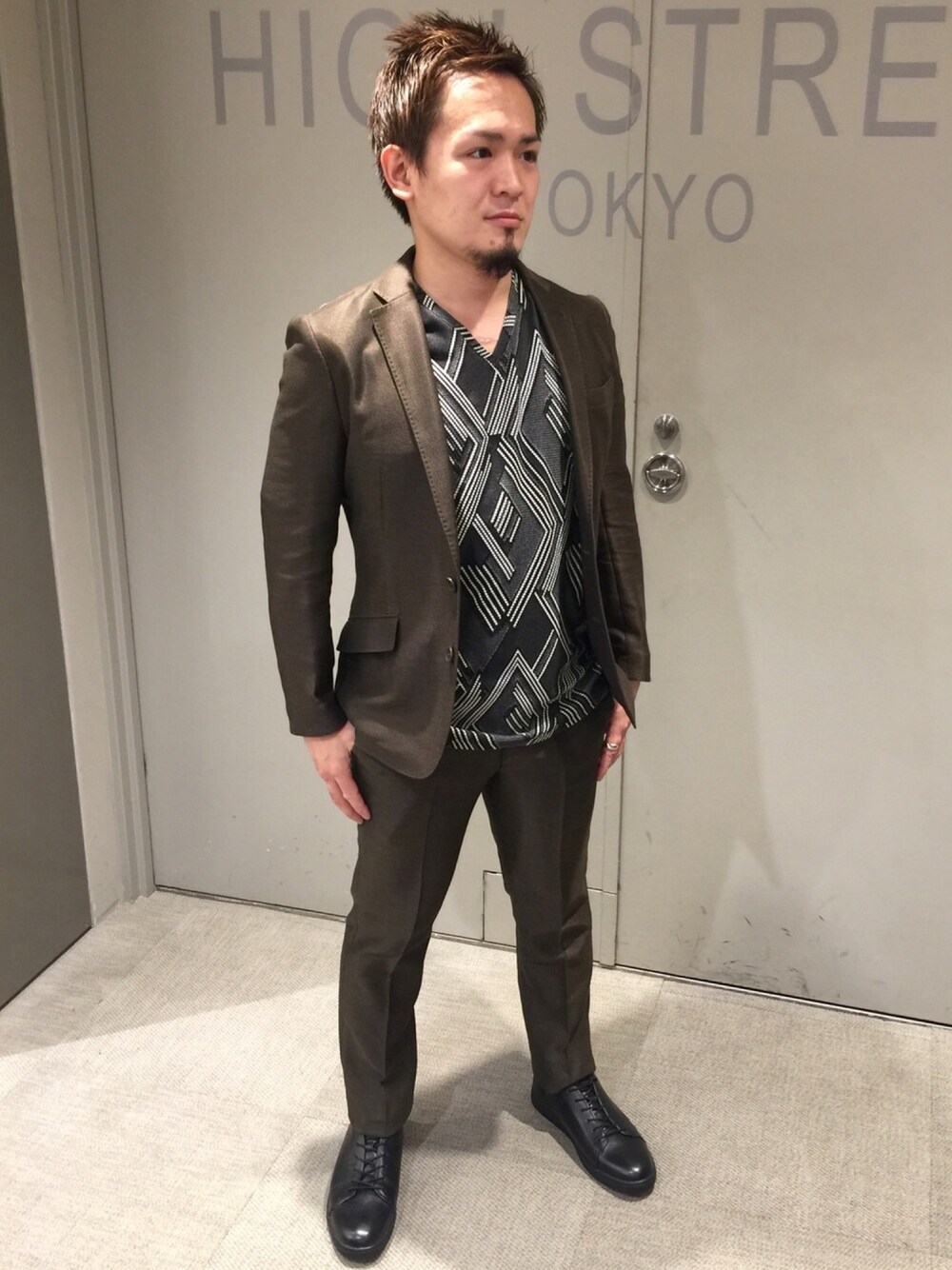 グリーン系のテーラードジャケット、グリーン系のスラックス、ブラック系のTシャツ/カットソーを着用したメンズの夏コーディネートの1枚目の写真