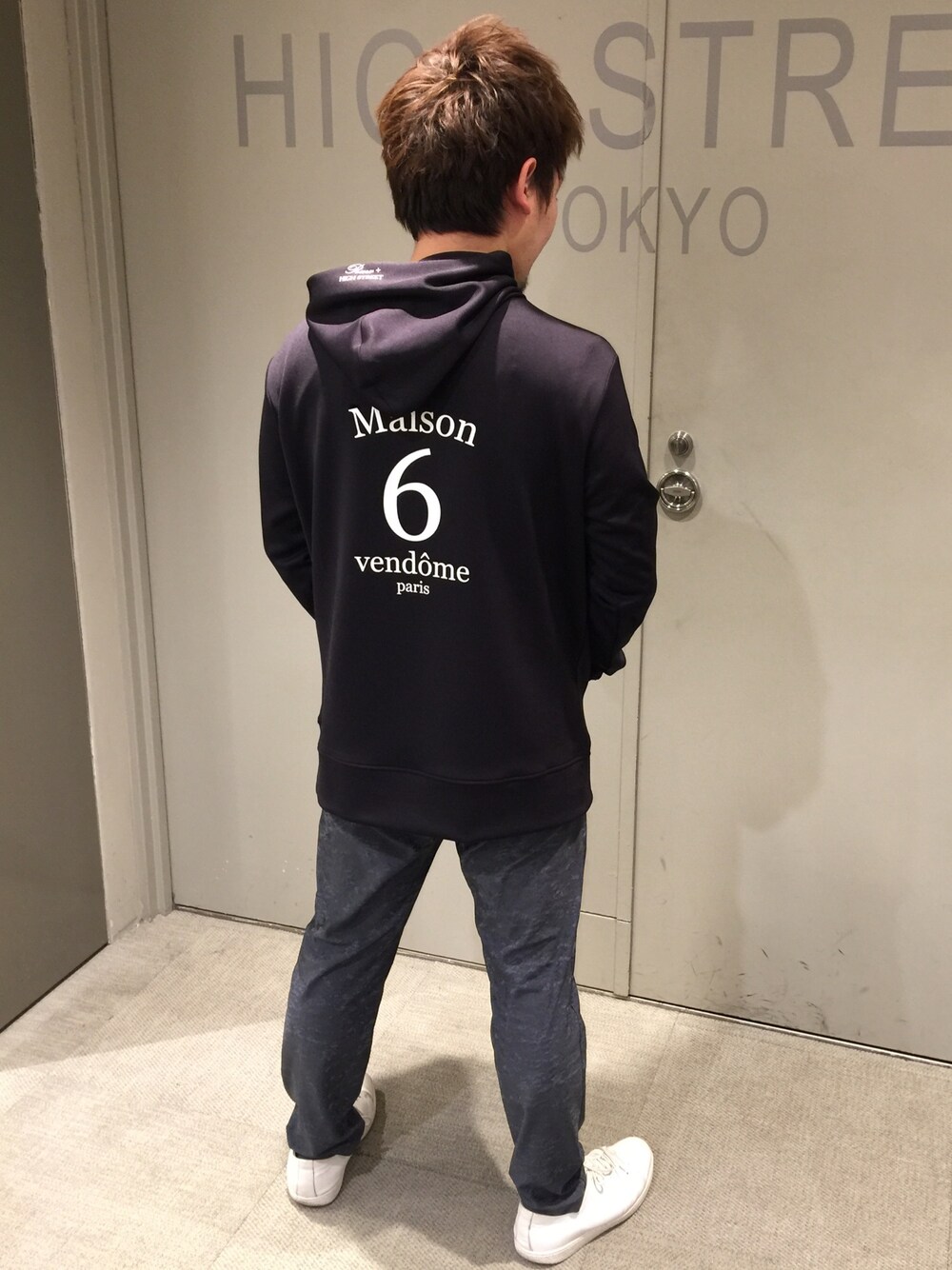 ブラック系のトップス、ブルー系のパンツ、ホワイト系のシューズを着用したメンズの春コーディネートの1枚目の写真