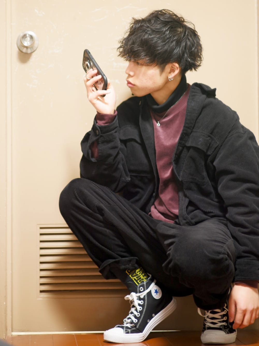 ブラック系のパンツ、ブラック系のトップス、レッド系のスウェットを着用したメンズの冬コーディネートの1枚目の写真