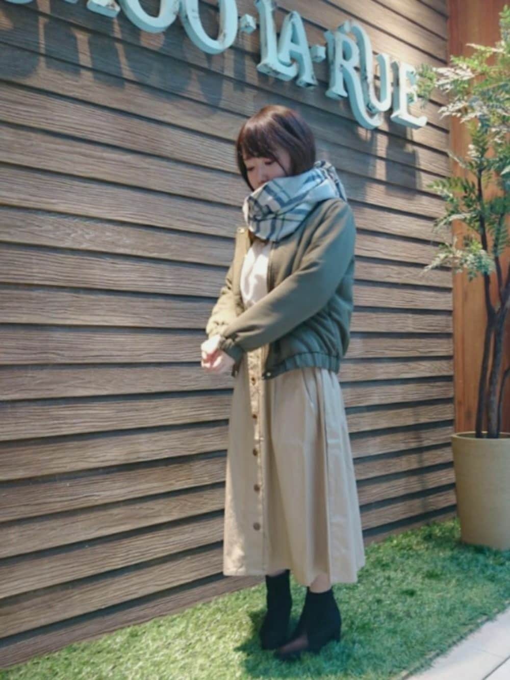 ベージュ系のスカート、ホワイト系のシャツ/ブラウス、グリーン系のノーカラージャケットを着用したレディースの秋コーディネートの1枚目の写真