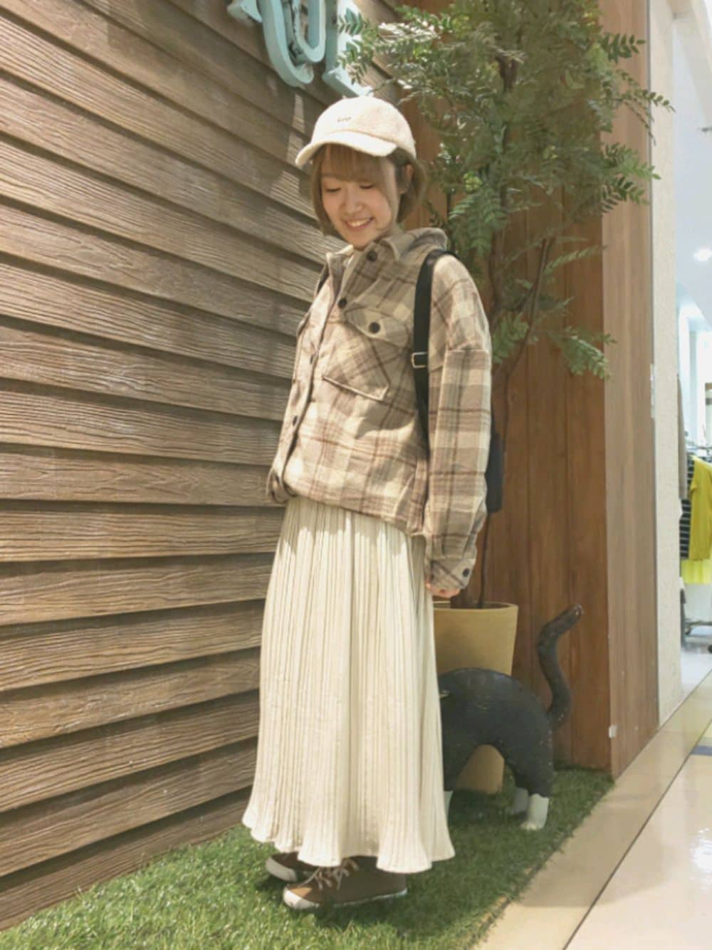 ベージュ系のスウェット、ブラック系のバックパック/リュック、イエロー系のミリタリージャケットを着用したレディースの秋コーディネートの1枚目の写真