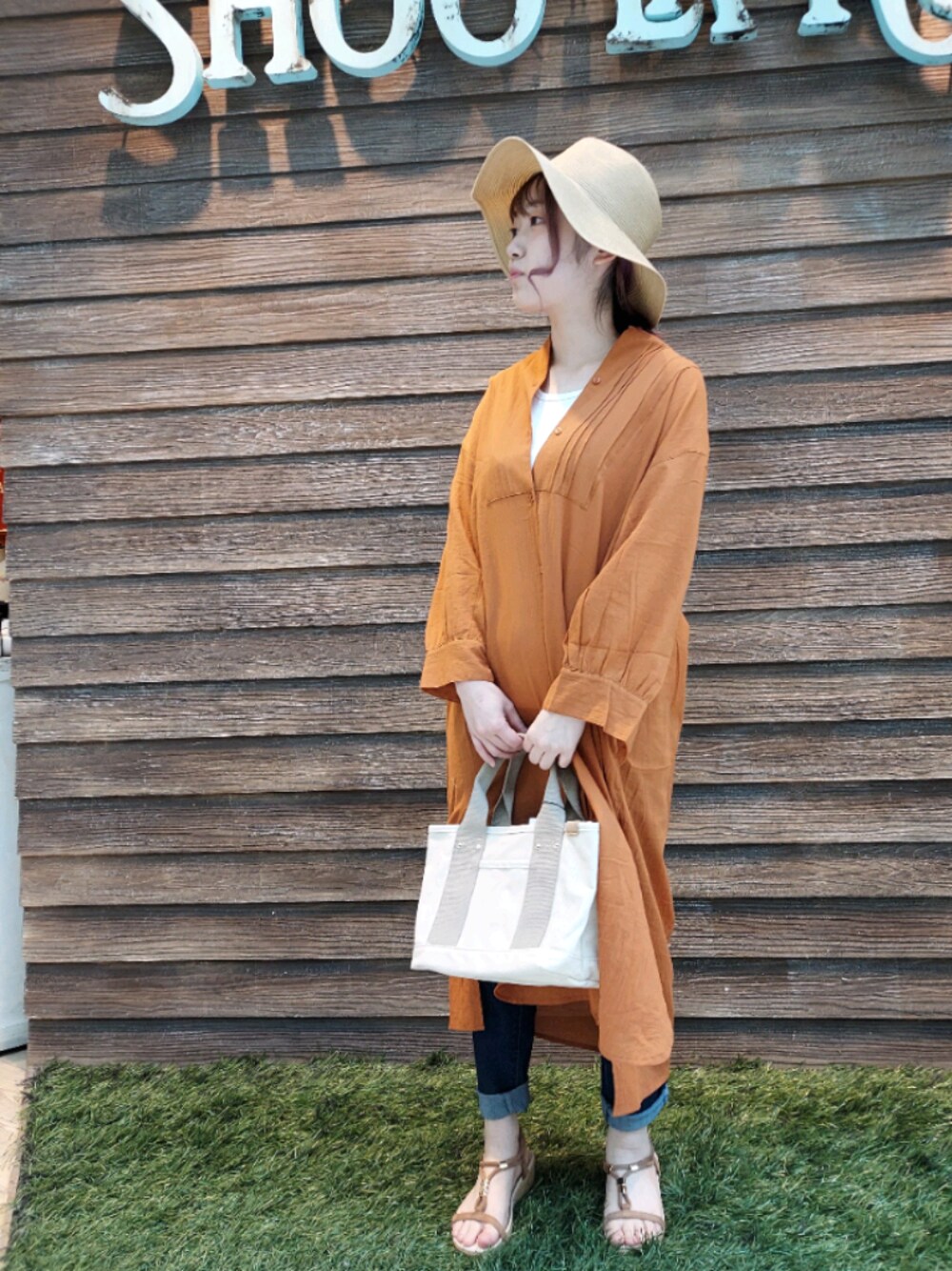 ブルー系のデニムパンツ、ブラウン系のサンダル、ベージュ系のトートバッグを着用したレディースの春コーディネートの1枚目の写真