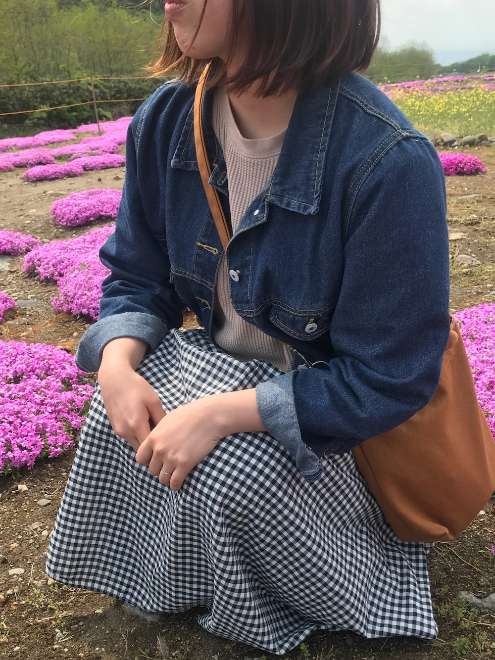 ブルー系のデニムジャケット、ベージュ系のTシャツ/カットソー、ブラウン系のバッグを着用したレディースの春コーディネートの1枚目の写真