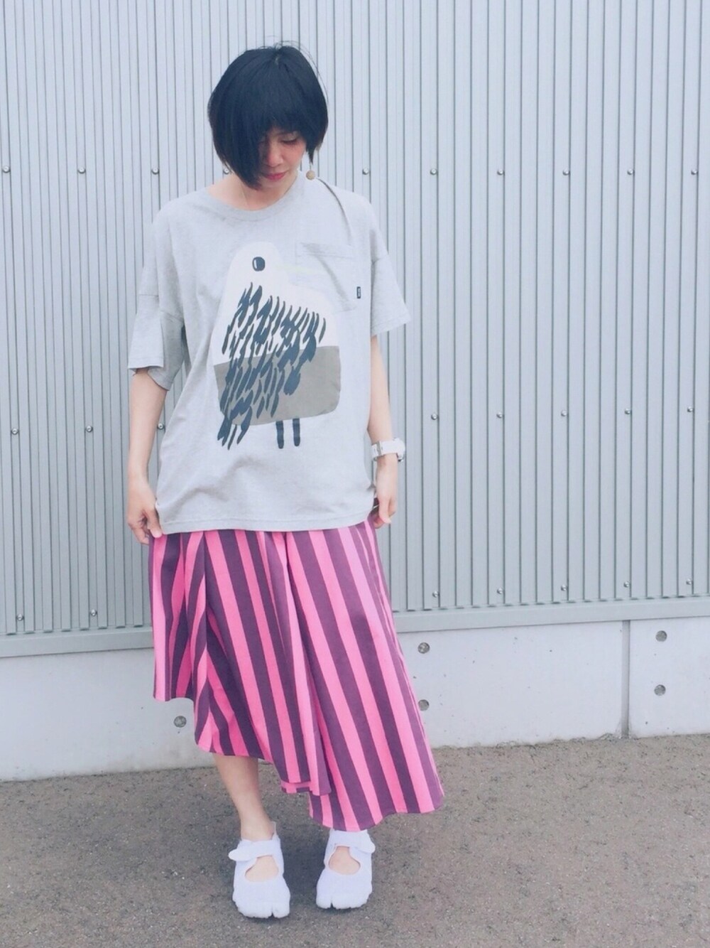 グレー系のTシャツ/カットソー、ピンク系のスカート、ホワイト系のスニーカーを着用したレディースの春コーディネートの1枚目の写真