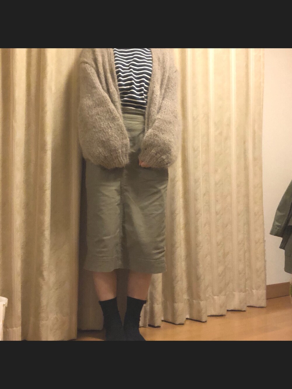 グリーン系のスカート、グレー系のカーディガン/ボレロ、ブルー系のTシャツ/カットソーを着用したレディースの秋コーディネートの1枚目の写真