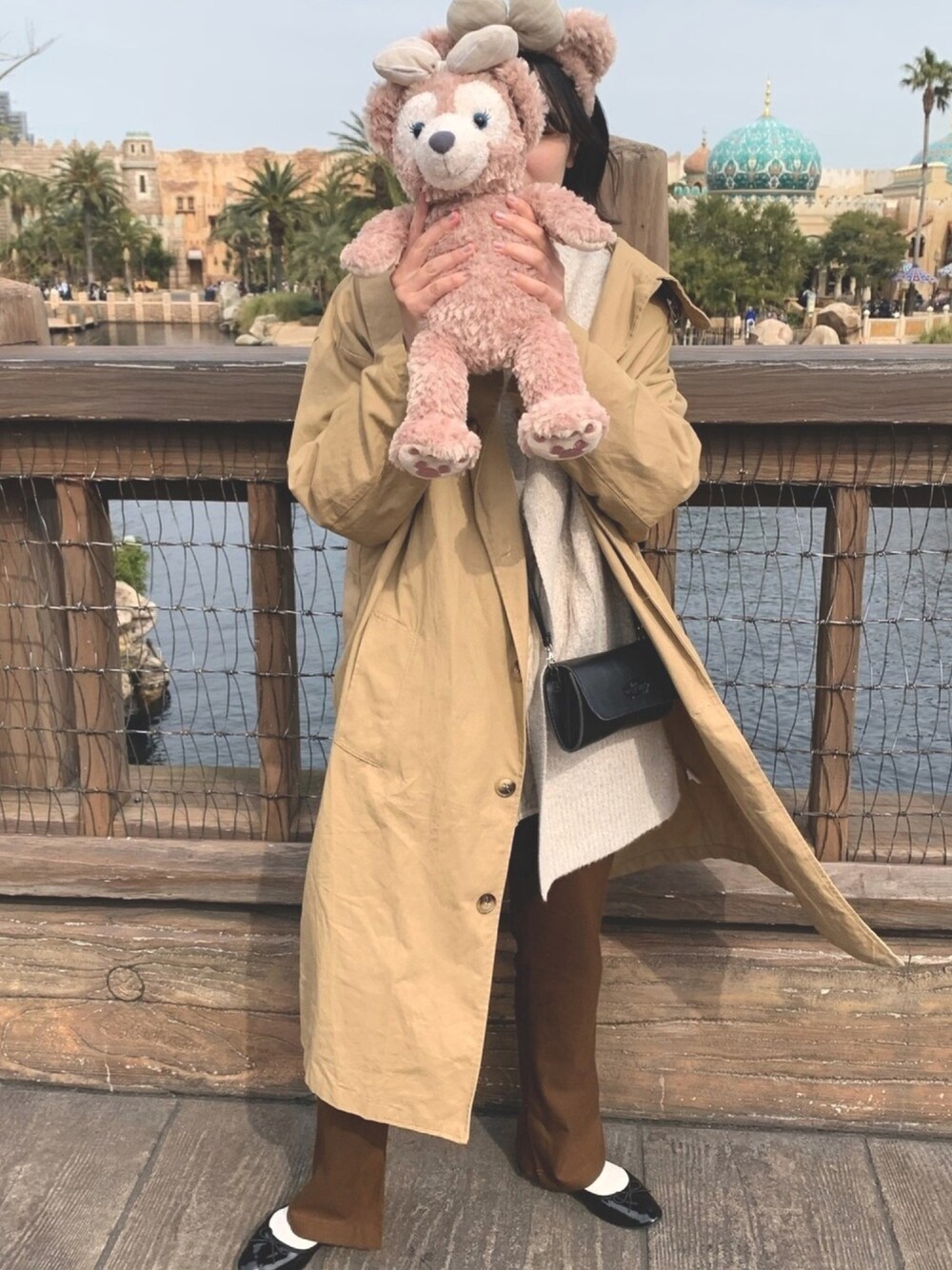 ベージュ系のトレンチコート、イエロー系のベスト、ブラウン系のスラックスを着用したレディースの春コーディネートの1枚目の写真