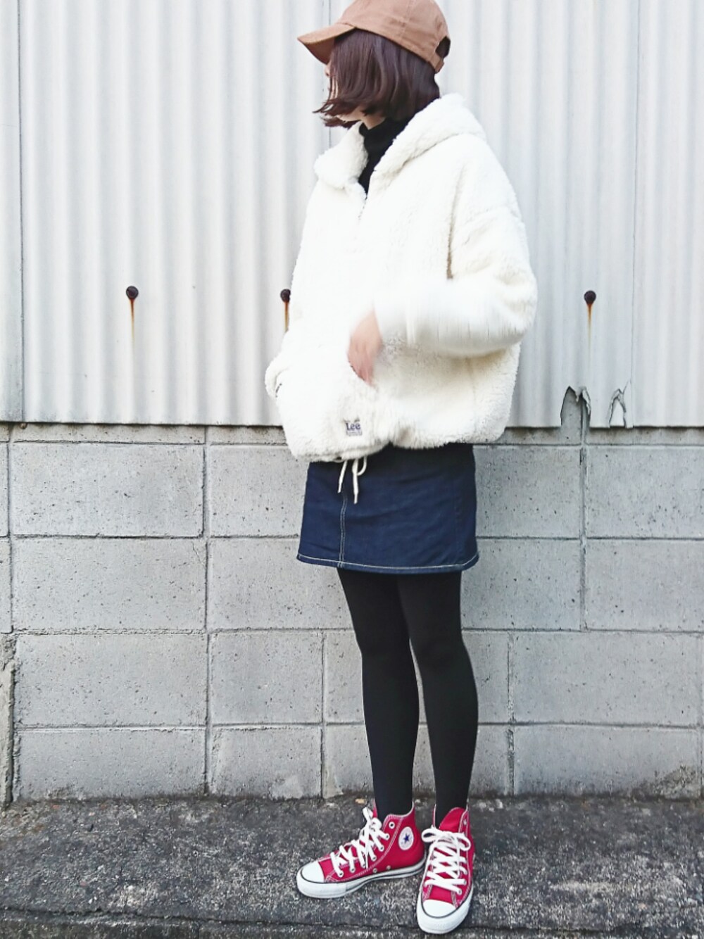 ブルー系のデニムスカート、ホワイト系のパーカー、レッド系のスニーカーを着用したレディースの秋コーディネートの1枚目の写真