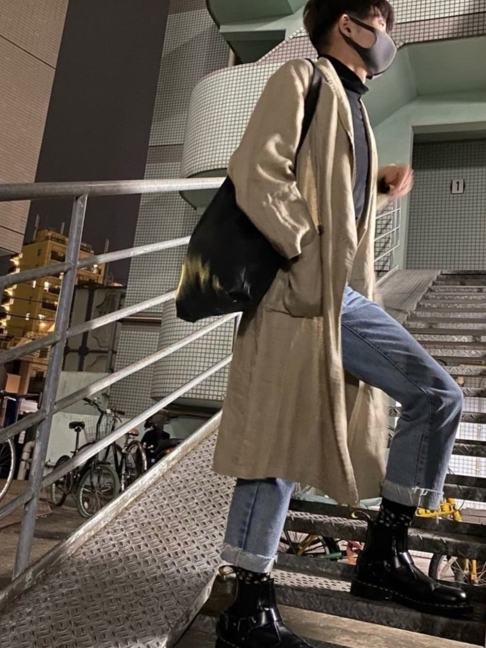 ブラック系のTシャツ/カットソー、ベージュ系のステンカラーコート、ブルー系のデニムパンツを着用したメンズの秋コーディネートの1枚目の写真