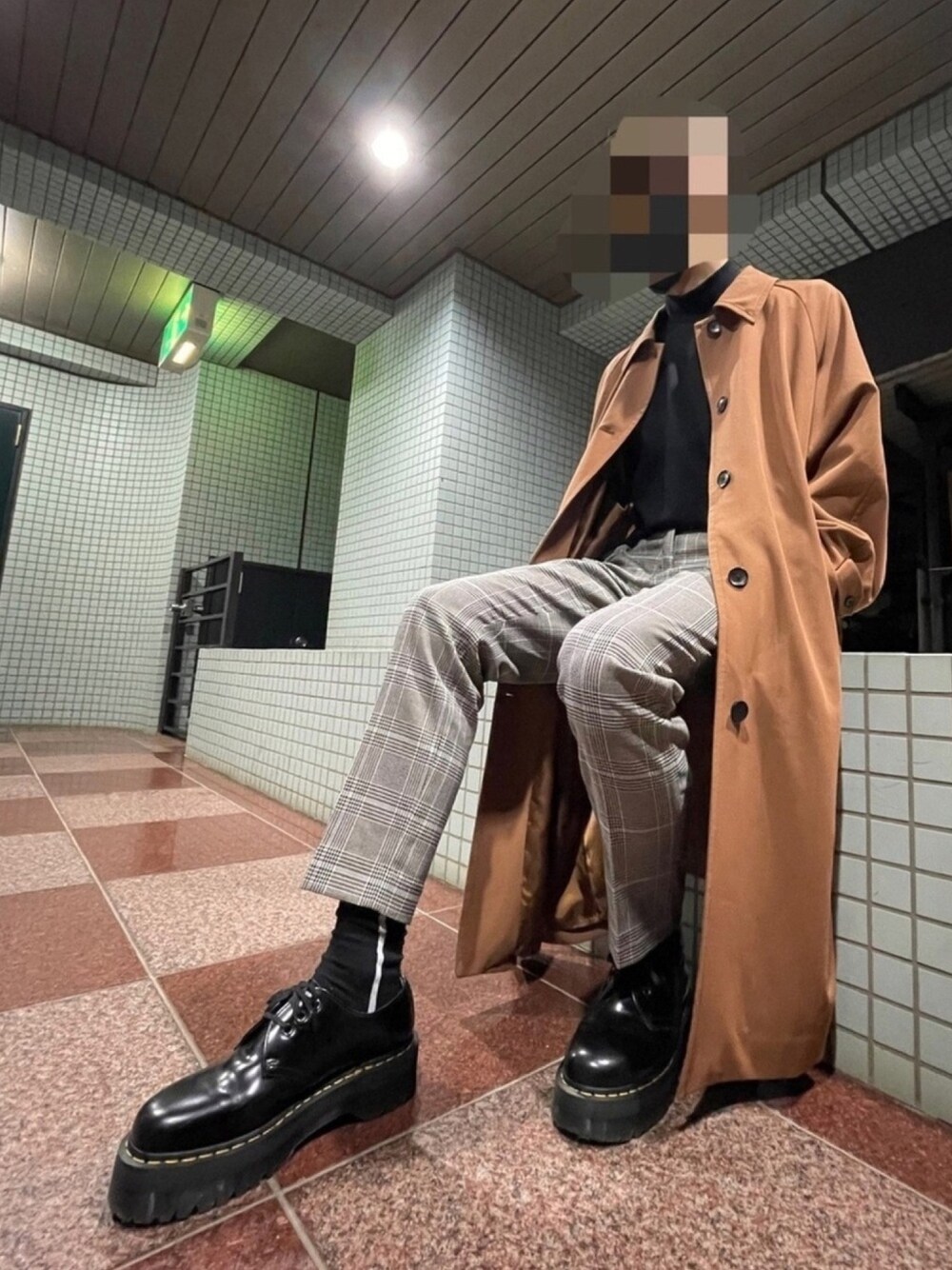 ブラック系のニット/セーター、ブラウン系のステンカラーコート、ベージュ系のスラックスを着用したメンズの秋コーディネートの1枚目の写真