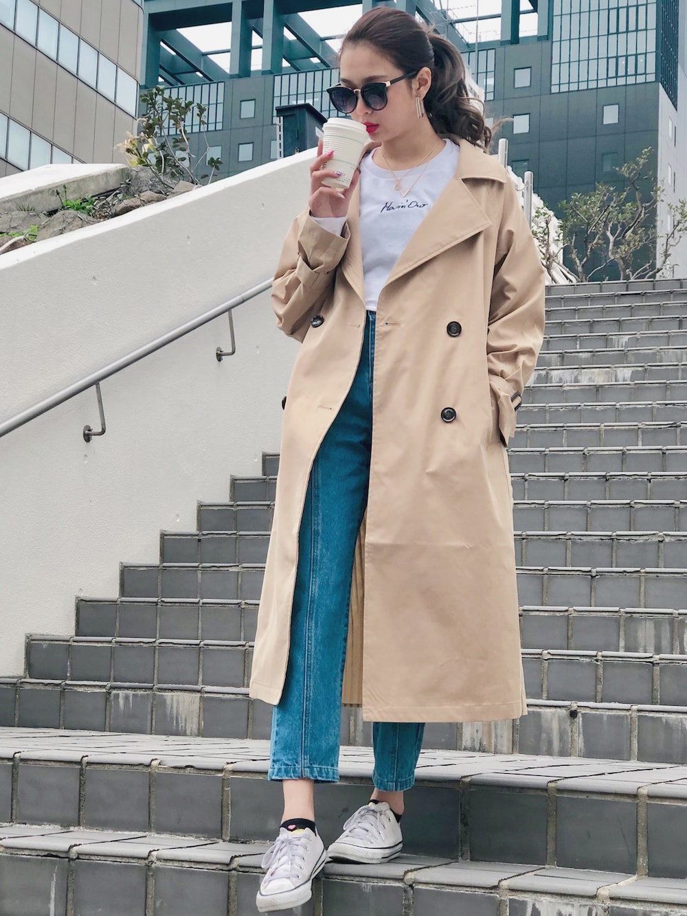 ベージュ系のトレンチコート、ブルー系のデニムパンツ、ホワイト系のスウェットを着用したレディースの春コーディネートの1枚目の写真