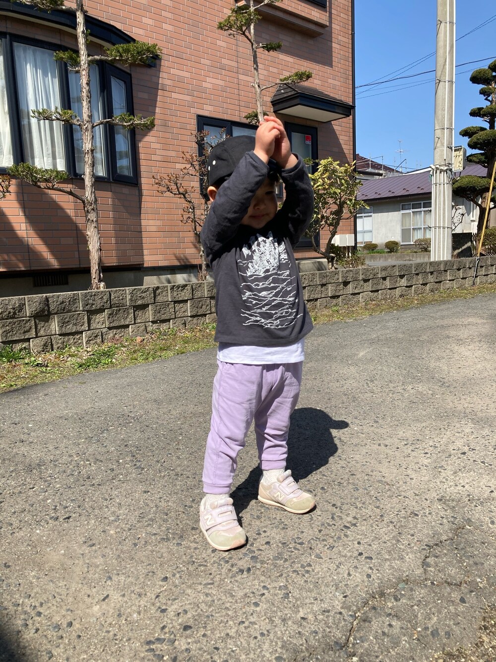 パープル系のパンツ、ピンク系のスニーカー、ブラック系のキャップを着用したキッズの春コーディネートの1枚目の写真