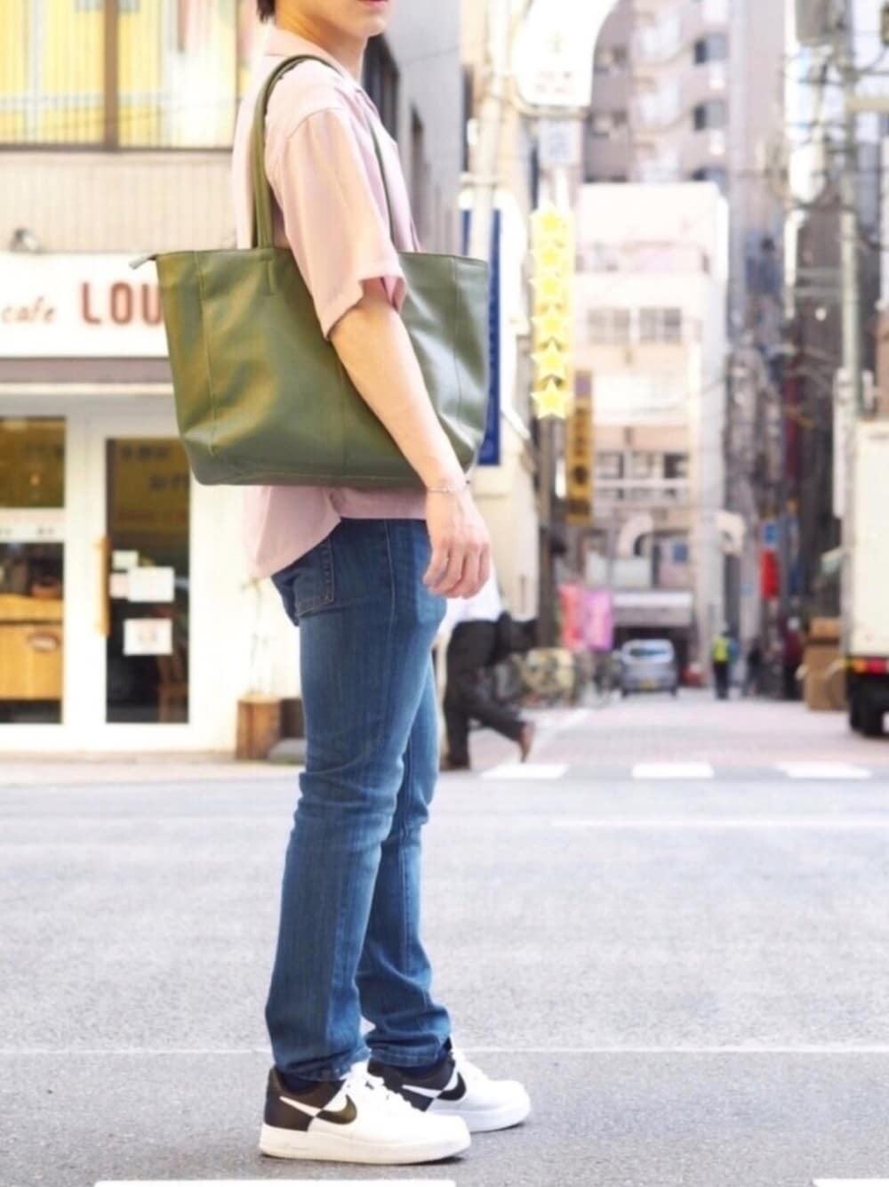 グリーン系のビジネスバッグ、ブルー系のデニムパンツ、ホワイト系のスニーカーを着用したメンズの夏コーディネートの1枚目の写真