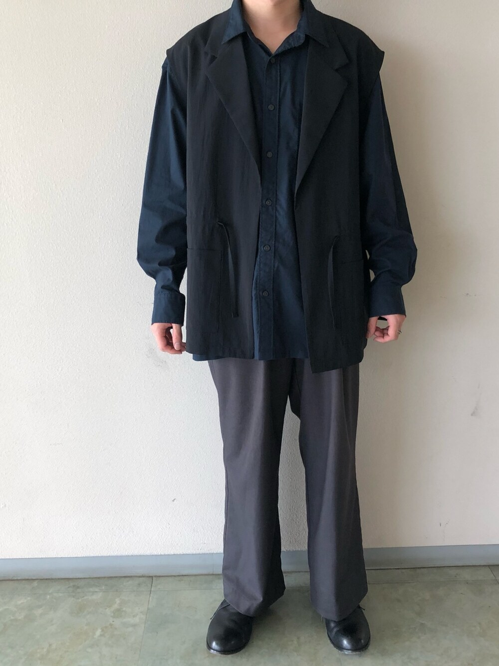 ブラック系のベスト、ブルー系のシャツ/ブラウス、グレー系のスラックスを着用したメンズの秋コーディネートの1枚目の写真