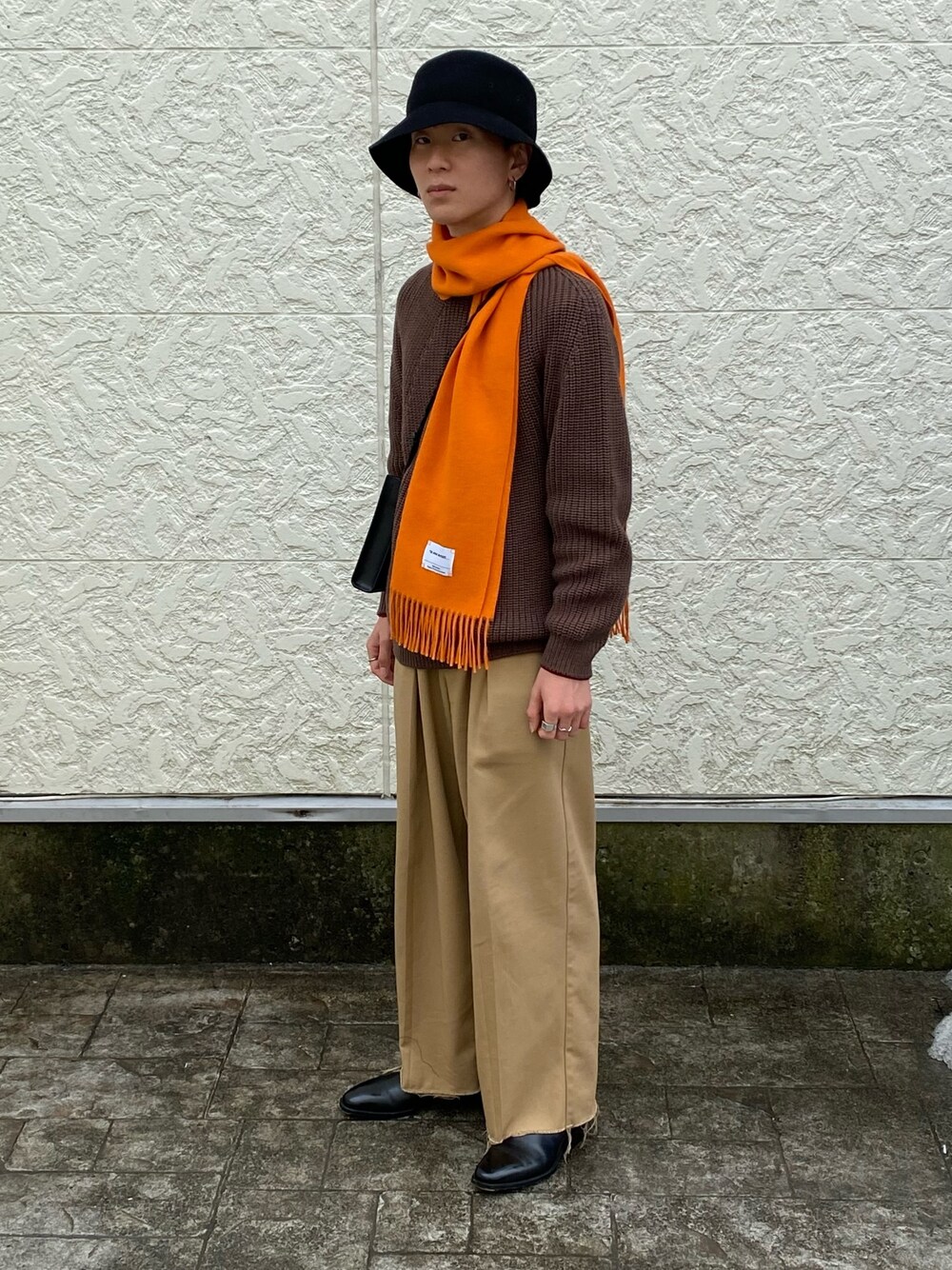 ブラウン系のニット/セーター、ベージュ系のパンツ、ブラック系のブーツを着用したメンズの冬コーディネートの1枚目の写真