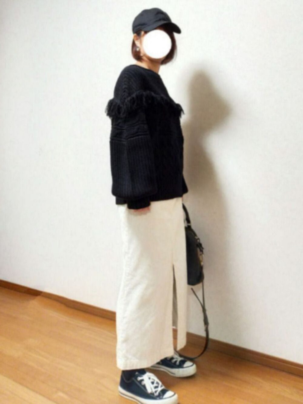 ブラック系のニット/セーター、ベージュ系のスカート、ブラック系のスニーカーを着用したレディースの冬コーディネートの1枚目の写真