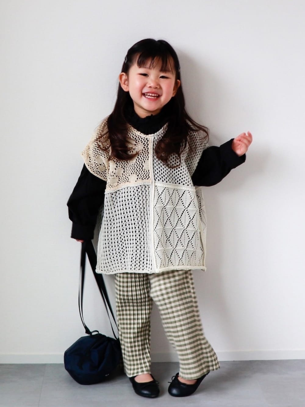「春めきシューズ、春コーデ、巾着バッグ、ニットベスト、フリルブラウス、ギンガムチェック、プリーツパンツ、バレエシューズ、3歳、おんなのこ」｜「b・ROOMのフリルネックギャザーボリュームブラウス（シャツ/ブラウス、ブラック系）」を使った、KISA / SANAさん（キッズ・90cm）の春コーディネートの1枚目の写真