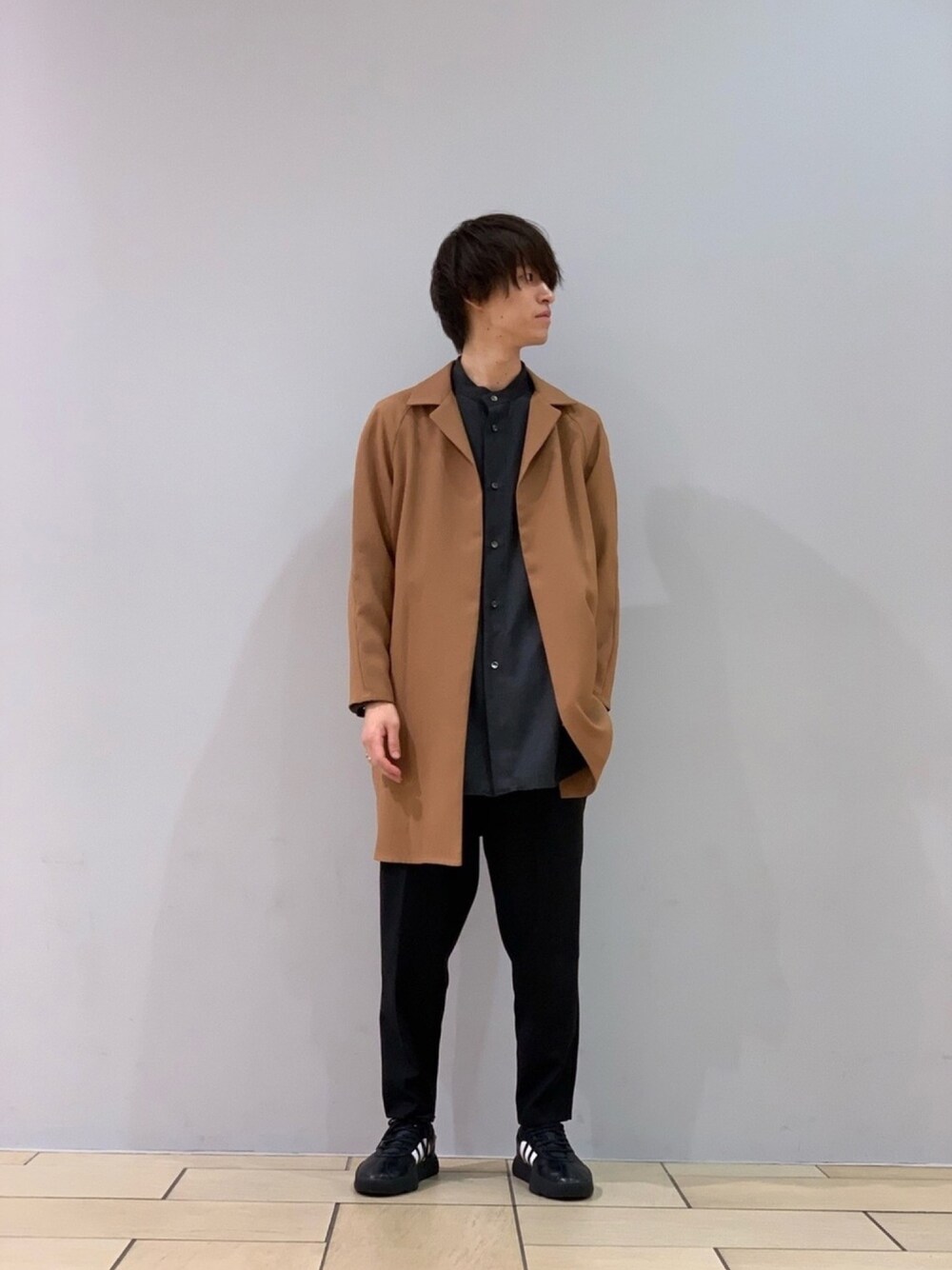 イエロー系のトレンチコート、グレー系のシャツ/ブラウス、ブラック系のスラックスを着用したメンズの秋コーディネートの1枚目の写真