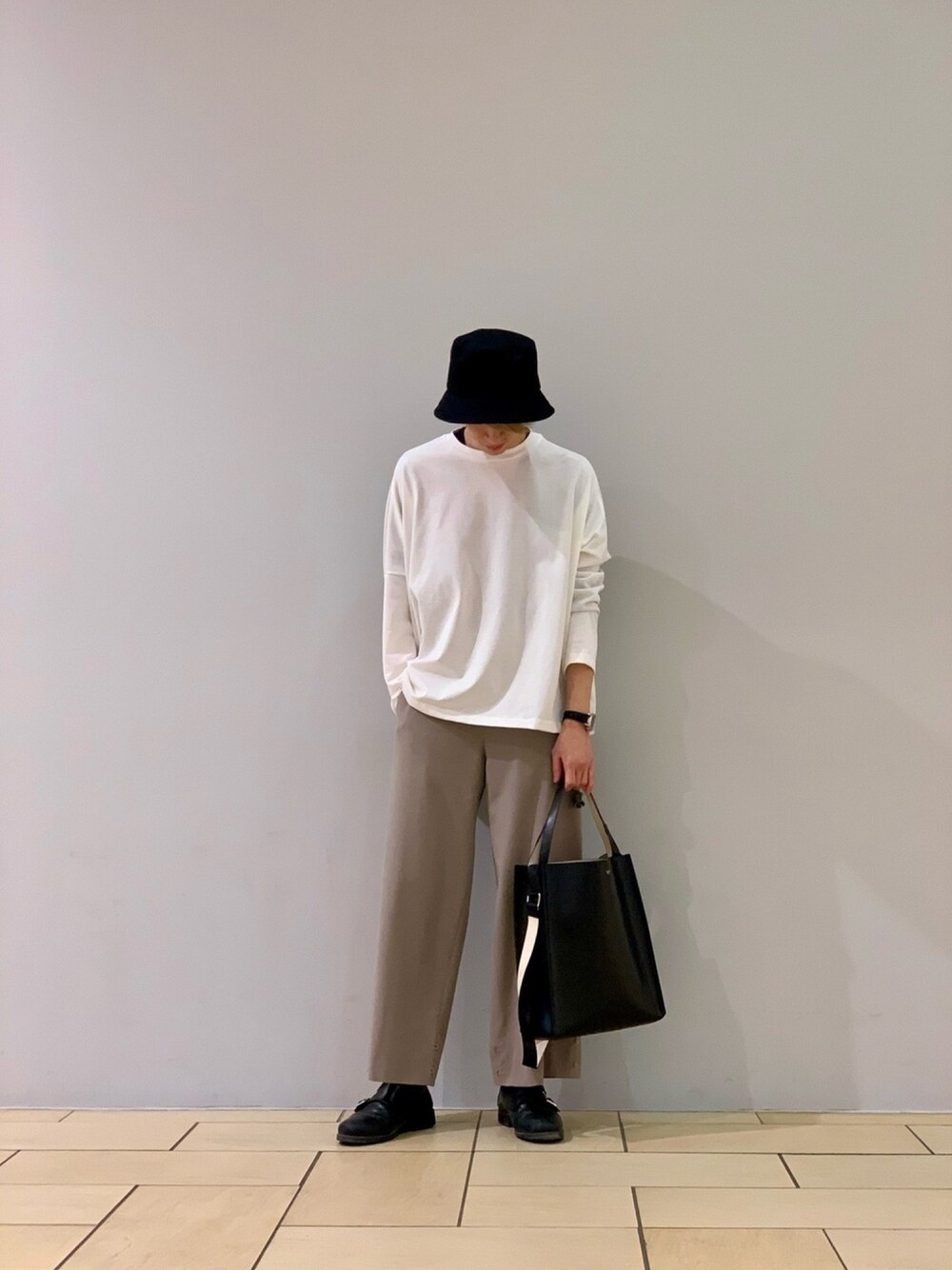 ホワイト系のTシャツ/カットソー、ブラック系のトートバッグ、ベージュ系のパンツを着用したメンズの冬コーディネートの1枚目の写真