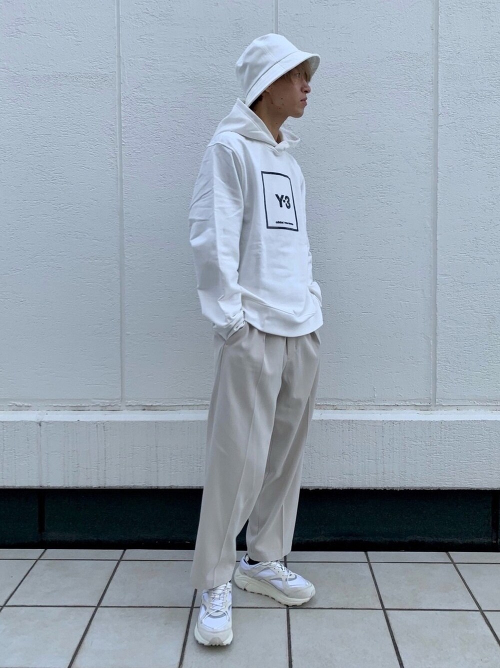 ホワイト系のパーカー、ベージュ系のスラックス、ホワイト系のスニーカーを着用したメンズの春コーディネートの1枚目の写真