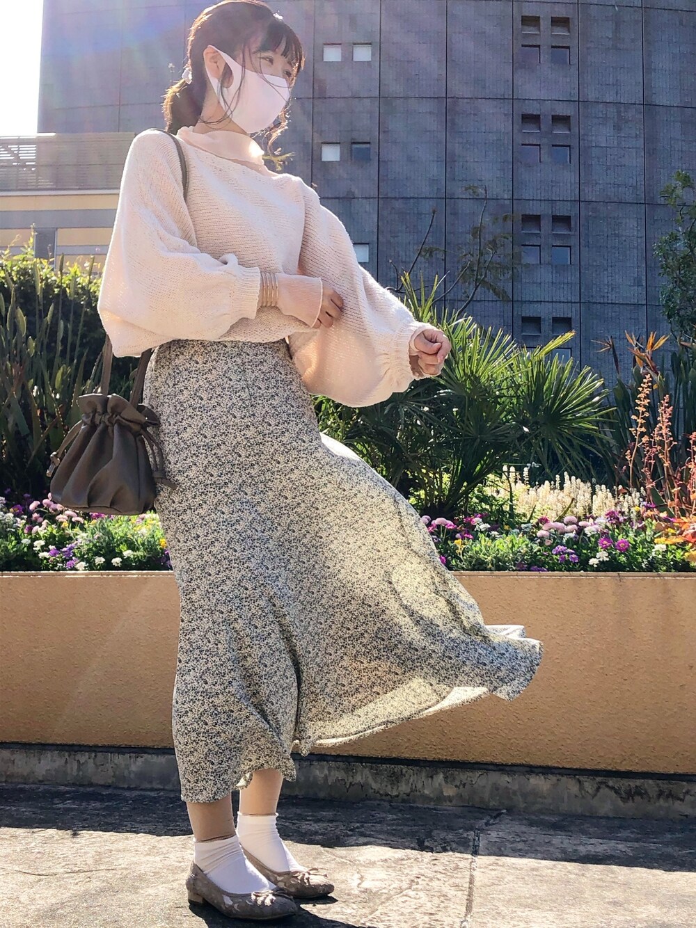 グリーン系のスカート、ブラウン系のトートバッグ、ブラウン系のバレエシューズを着用したレディースの春コーディネートの1枚目の写真