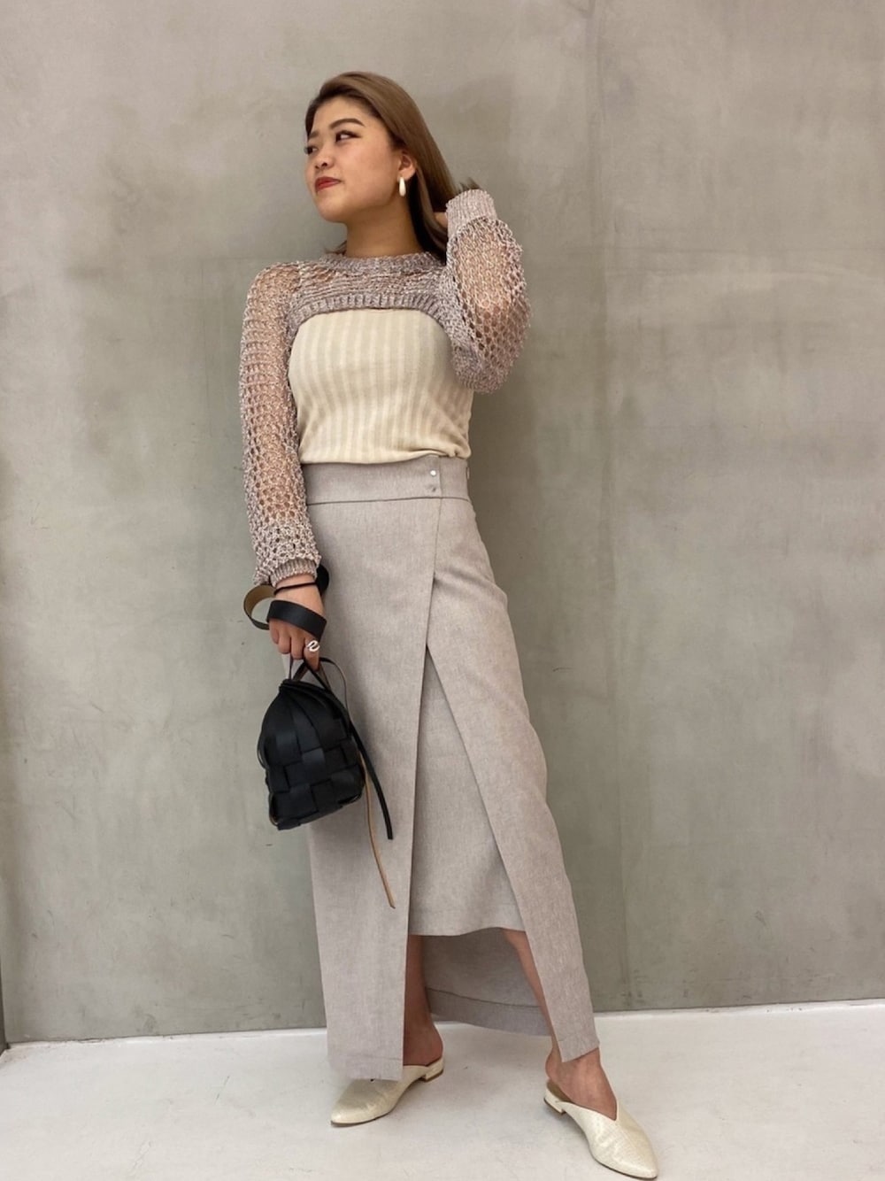 ベージュ系のスカート、ホワイト系のサンダル、ブラック系のバッグを着用したレディースの春コーディネートの1枚目の写真