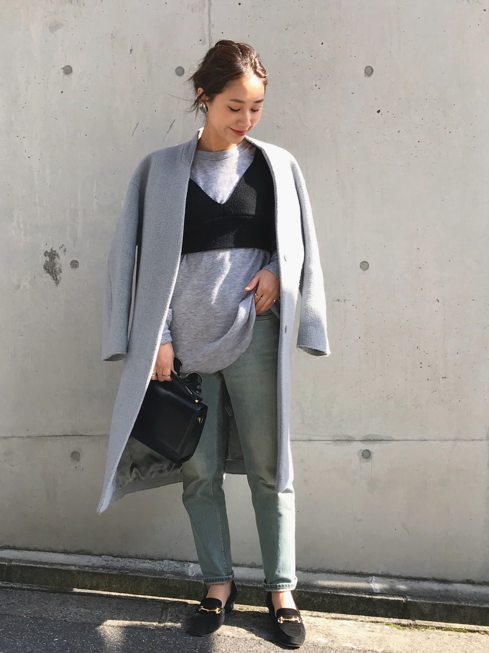 グレー系のチェスターコート、ブルー系のデニムパンツ、グレー系のスウェットを着用したレディースの冬コーディネートの1枚目の写真