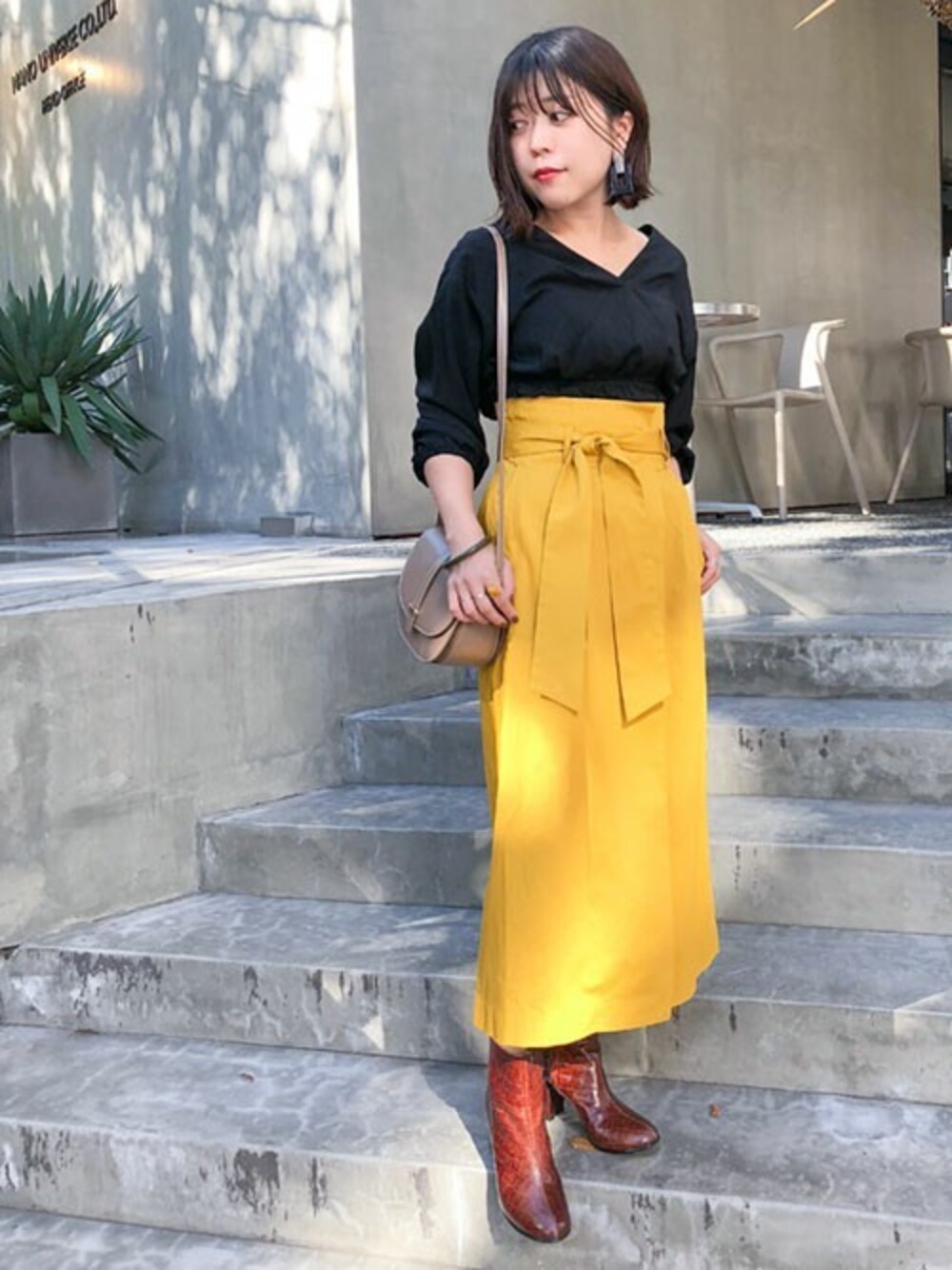 ブラック系のシャツ/ブラウス、イエロー系のスカート、グレー系のショルダーバッグを着用したレディースの秋コーディネートの1枚目の写真