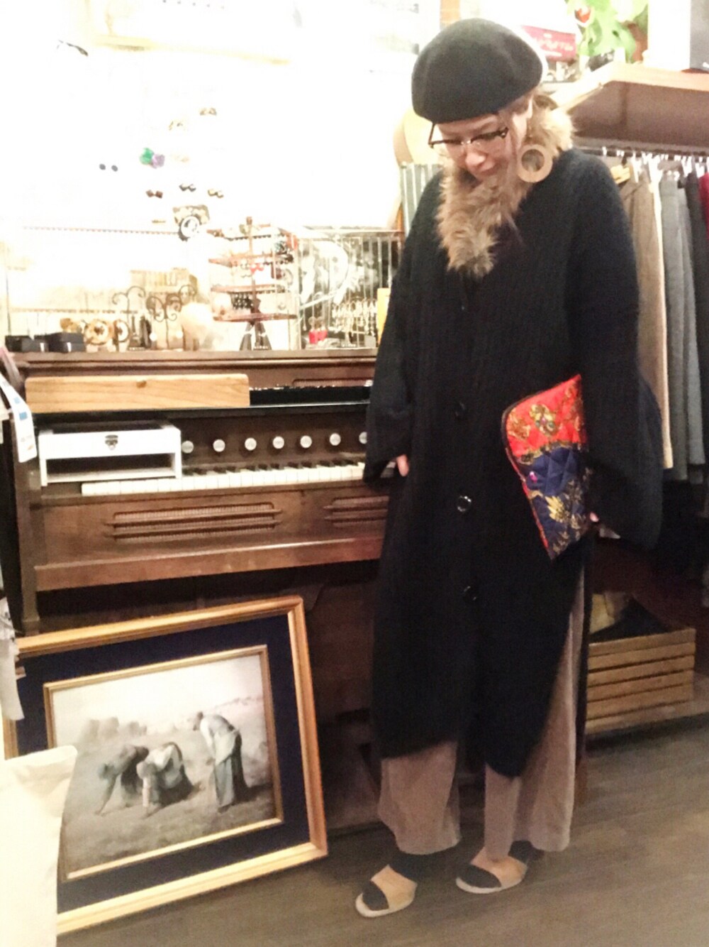 ブラック系のカーディガン/ボレロ、ブラック系のジャケット/アウター、レッド系のクラッチバッグを着用したレディースの冬コーディネートの1枚目の写真