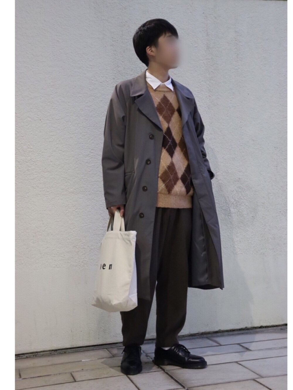 グレー系のチェスターコート、ベージュ系のニット/セーター、ホワイト系のシャツ/ブラウスを着用したメンズの冬コーディネートの1枚目の写真