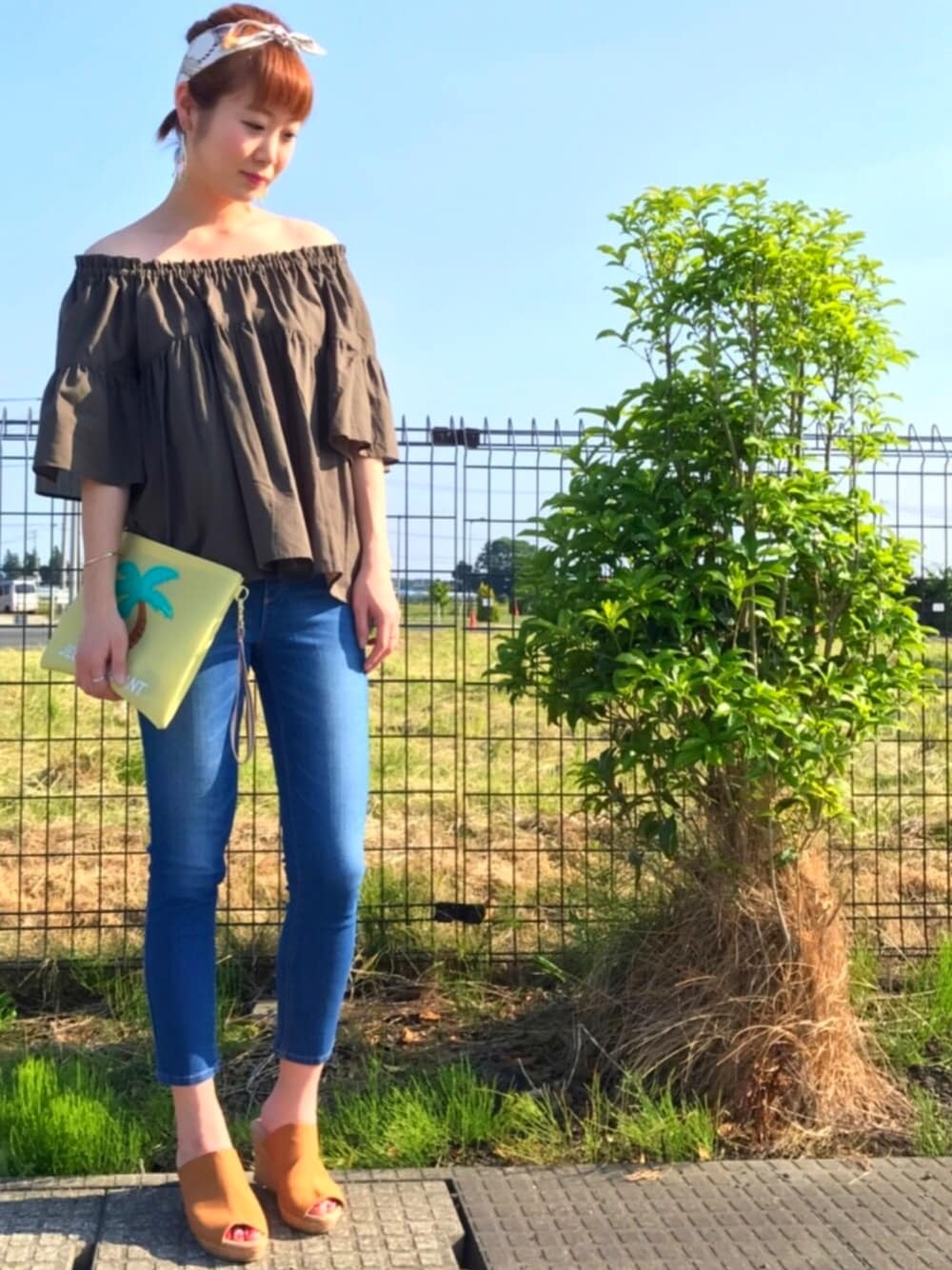 グリーン系のシャツ/ブラウス、イエロー系のバッグ、ブルー系のデニムパンツを着用したレディースの春コーディネートの1枚目の写真