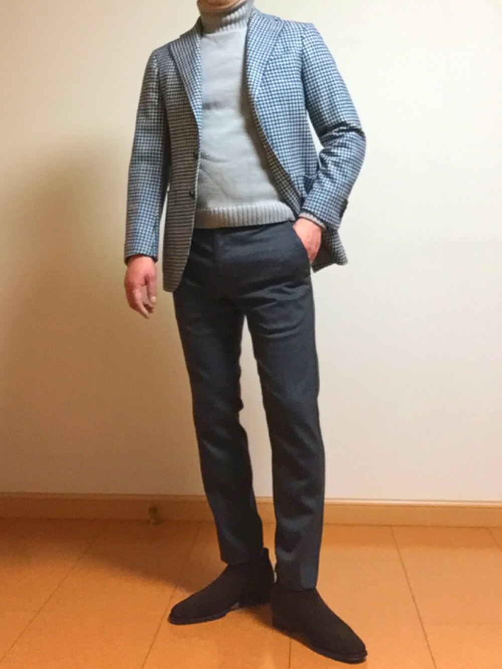 グレー系のスラックス、グレー系のニット/セーター、ブラウン系のブーティを着用したメンズの春コーディネートの1枚目の写真