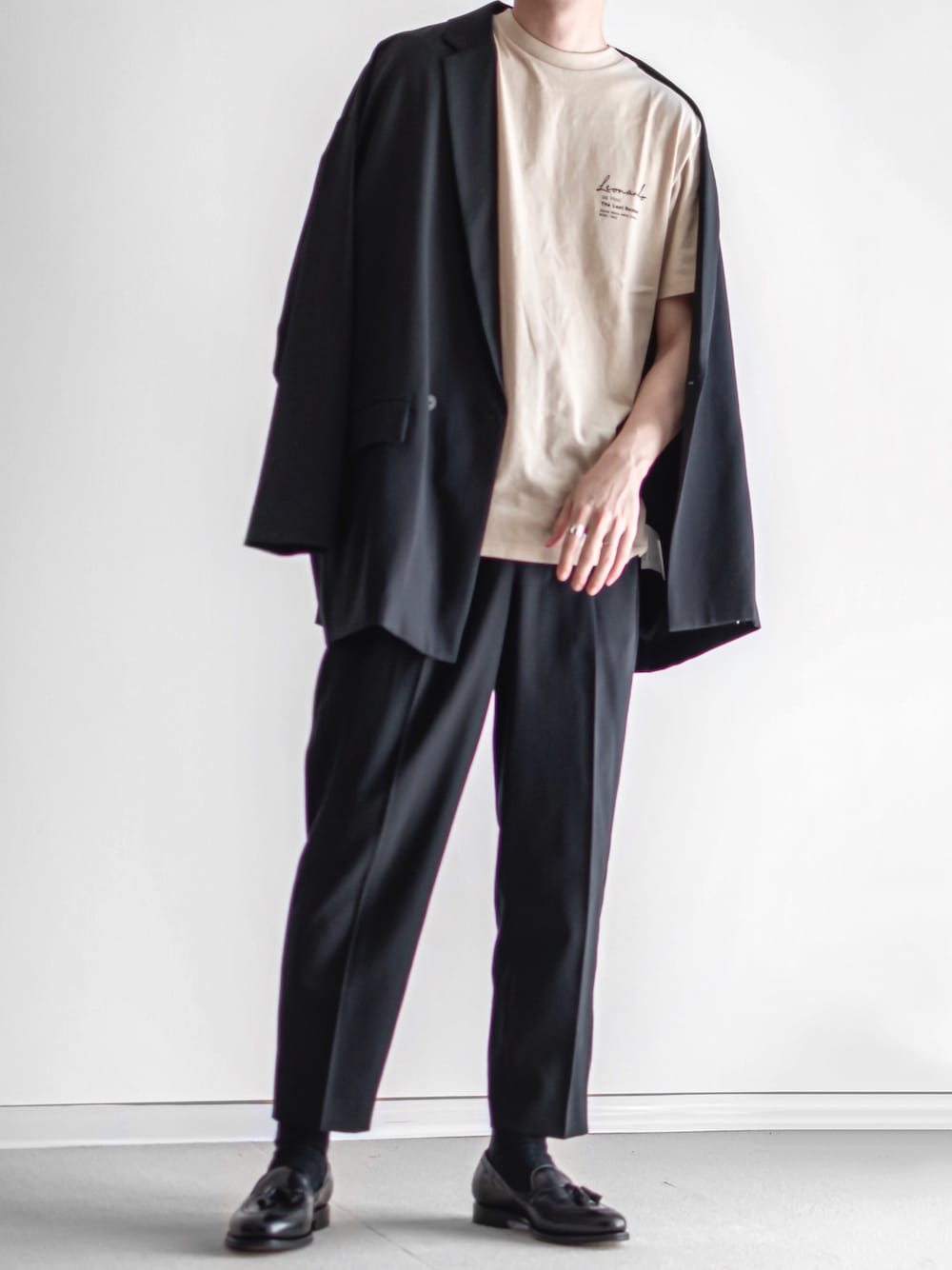 ベージュ系のTシャツ/カットソー、ブラック系のテーラードジャケット、ブラック系のスラックスを着用したメンズの春コーディネートの1枚目の写真