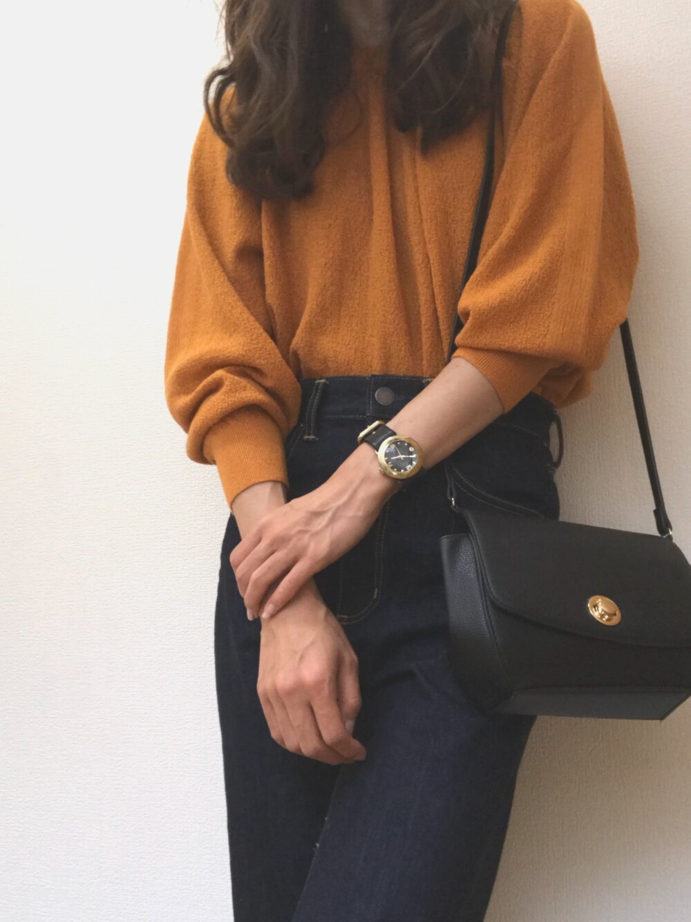 オレンジ系のニット/セーター、ブルー系のデニムパンツ、ブラック系のショルダーバッグを着用したレディースの夏コーディネートの1枚目の写真