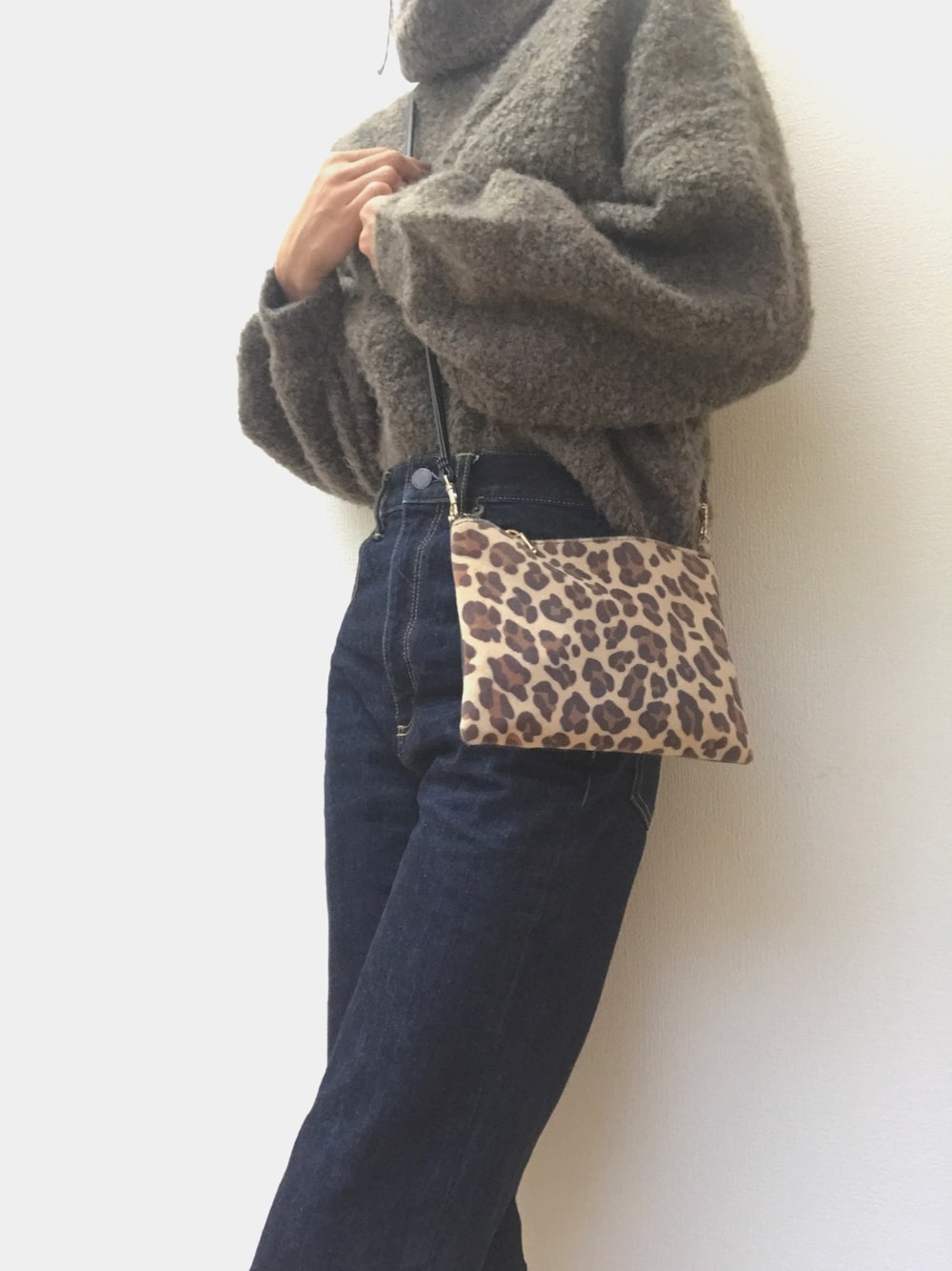 ブラウン系のニット/セーター、ブルー系のデニムパンツ、ブラウン系のショルダーバッグを着用したレディースの秋コーディネートの1枚目の写真