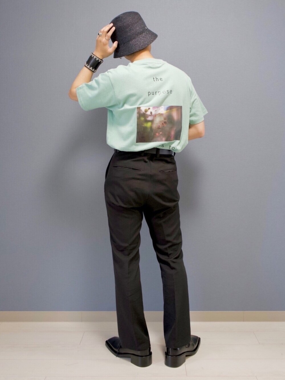 グリーン系のTシャツ/カットソー、ブラック系のスラックス、ブラック系のシューズを着用したメンズの春コーディネートの1枚目の写真