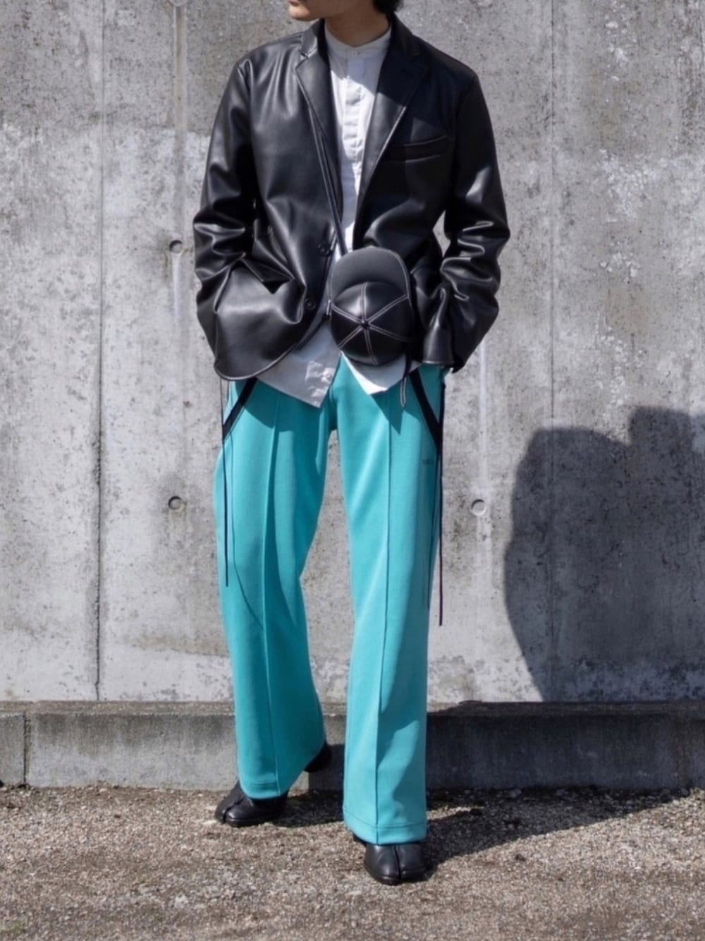 ブラック系のテーラードジャケット、ブラック系のショルダーバッグ、グリーン系のその他パンツを着用したメンズの春コーディネートの1枚目の写真