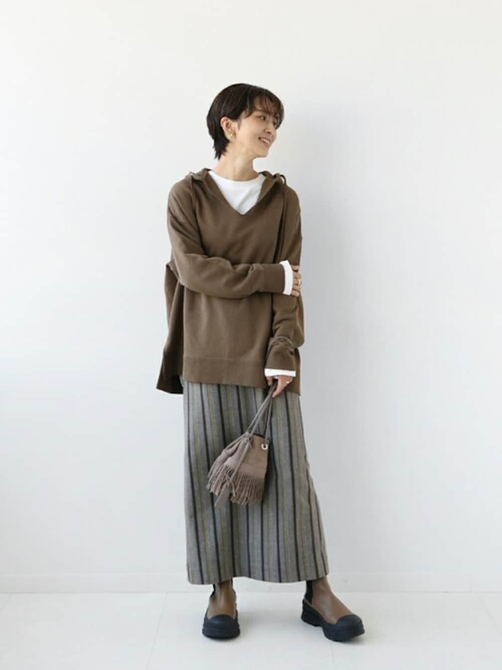 ブラウン系のスカート、ブラウン系のハンドバッグ、ブラウン系のスウェットを着用したレディースの秋コーディネートの1枚目の写真