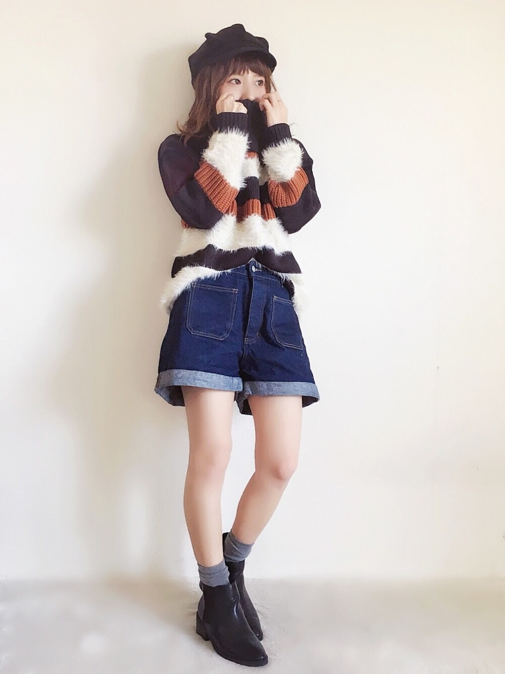 ブラック系のニット/セーター、ブルー系のデニムパンツ、ブラック系のブーツを着用したレディースの秋コーディネートの1枚目の写真