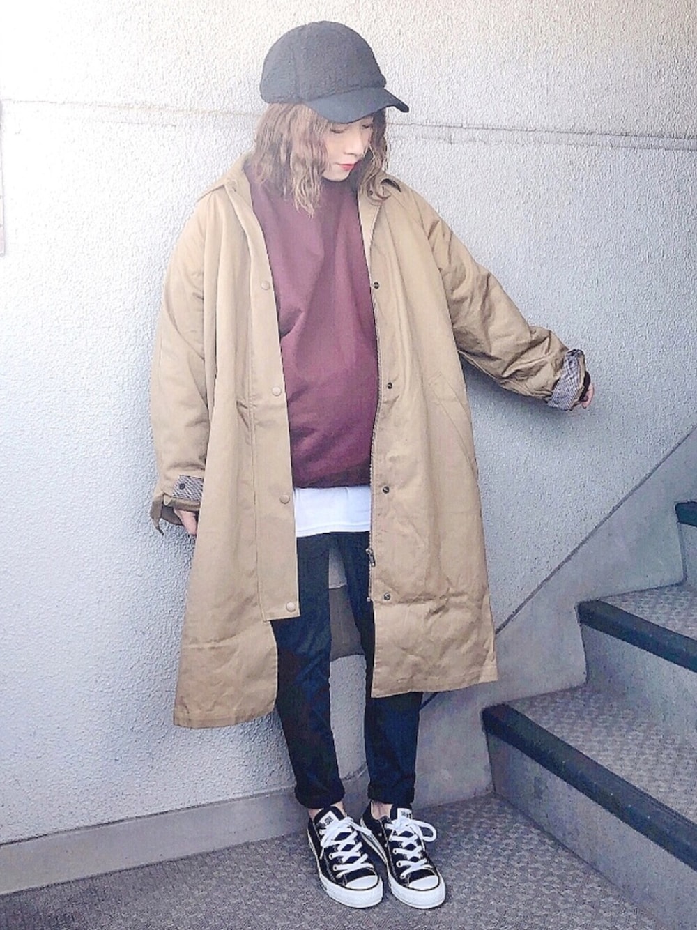 ベージュ系のステンカラーコート、レッド系のスウェット、ホワイト系のTシャツ/カットソーを着用したレディースの冬コーディネートの1枚目の写真