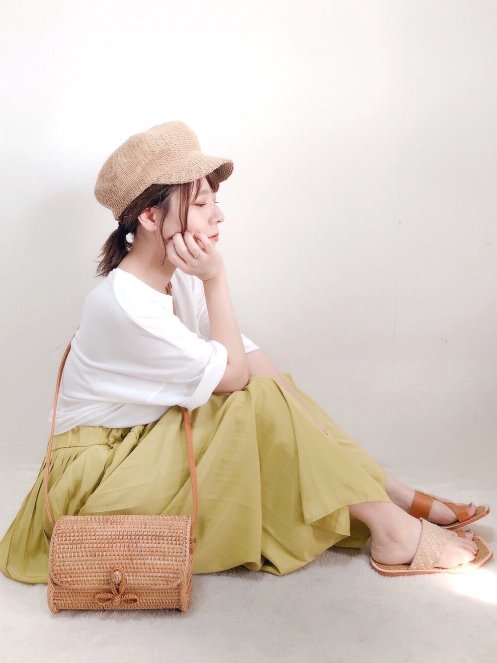 イエロー系のスカート、ベージュ系のサンダル、ベージュ系のショルダーバッグを着用したレディースの夏コーディネートの1枚目の写真