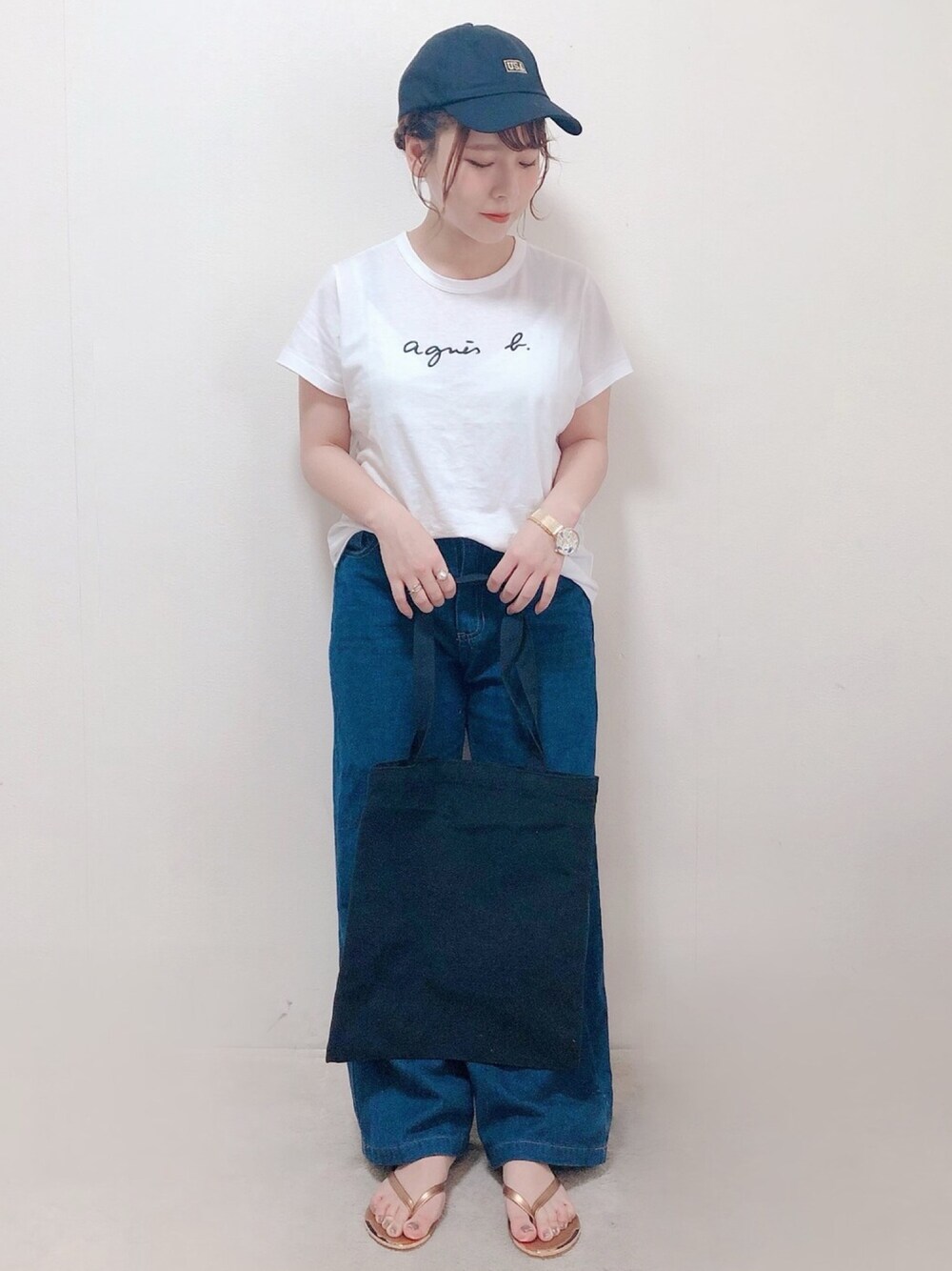 ホワイト系のTシャツ/カットソー、ブラック系のエコバッグ/サブバッグ、ゴールド系のサンダルを着用したレディースの夏コーディネートの1枚目の写真