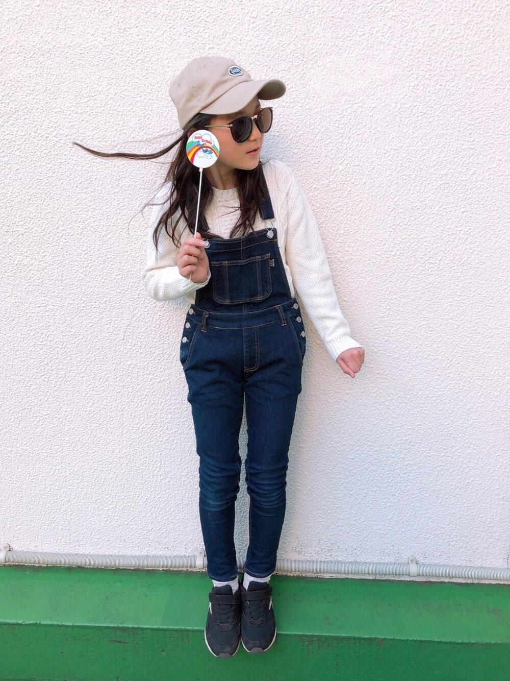 ブルー系のサロペット/オーバーオール、ブラック系のスニーカー、ベージュ系のキャップを着用したキッズの冬コーディネートの1枚目の写真