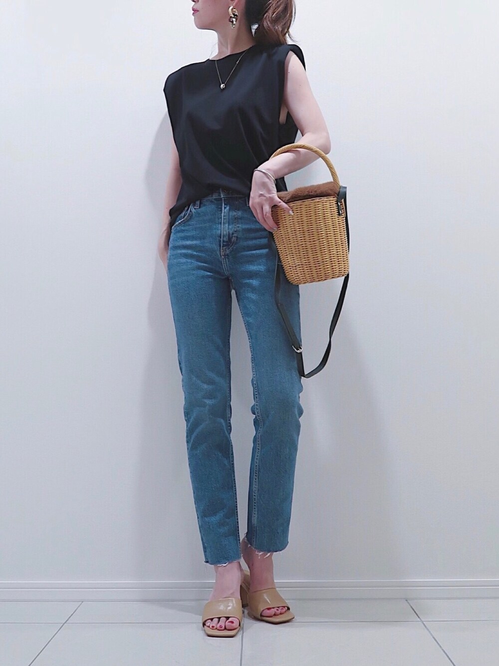 ブラウン系のかごバッグ、ブルー系のデニムパンツ、ブラック系のTシャツ/カットソーを着用したレディースの秋コーディネートの1枚目の写真