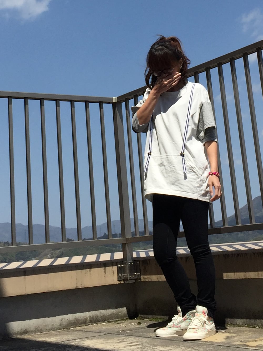 ホワイト系のスニーカー、ブラック系のデニムパンツ、グレー系のTシャツ/カットソーを着用したレディースの春コーディネートの1枚目の写真