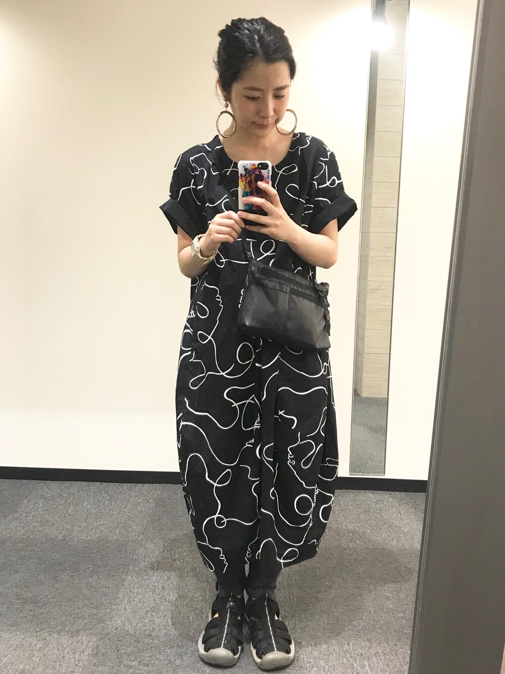 ブラック系のショルダーバッグ、ブラック系のサンダル、ブラック系のワンピースを着用したレディースの夏コーディネートの1枚目の写真